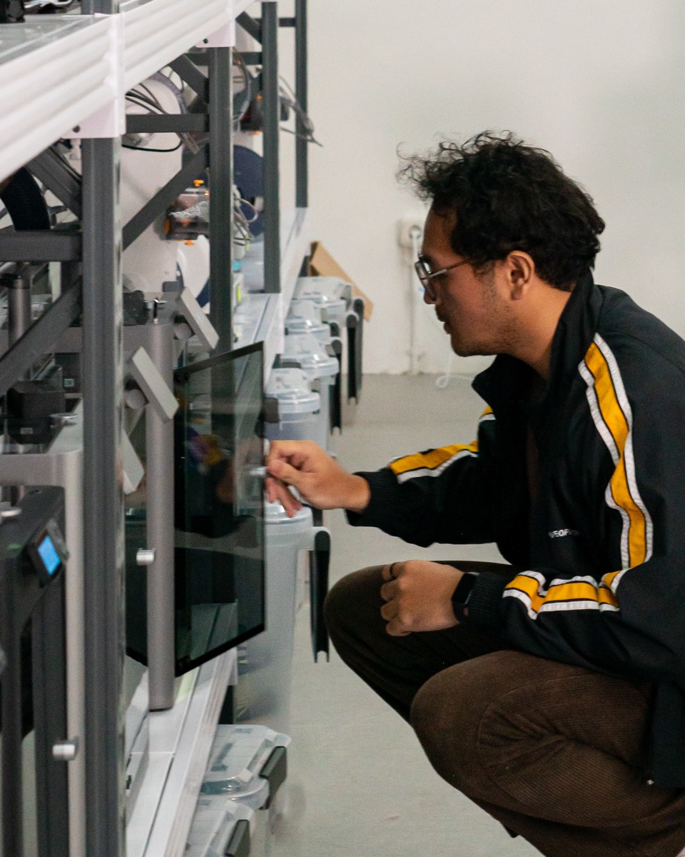 A maker adjusting one of the studio's 3D printers